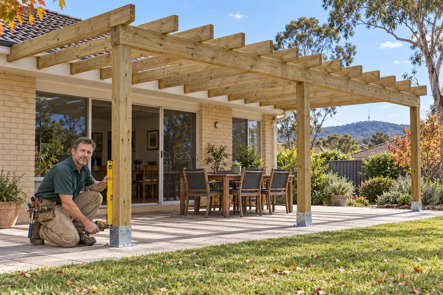 Pergola, Canberra: carpenter fixing a rafter on a new freestanding timber pergola frame over a paved patio
